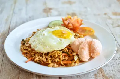 a plate of food with an egg on top of noodles at Palm Garden Bali in Nusa Dua