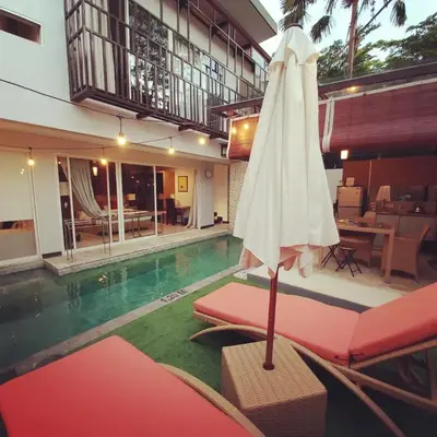 a white umbrella sitting on a bench next to a pool at PalmA Private Villa - A Leafy Place in Mumbul Hill in Nusa Dua