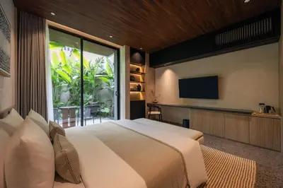 a bedroom with a large bed and a large window at Marvee Suites Bali in Canggu