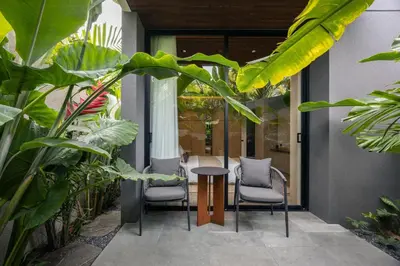 a patio with chairs and a table and some plants at Marvee Suites Bali in Canggu