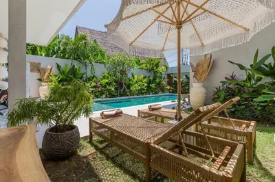 a patio with a table and umbrella and a pool at Villa Jazz 3BR 10m Pool seminyak in Seminyak