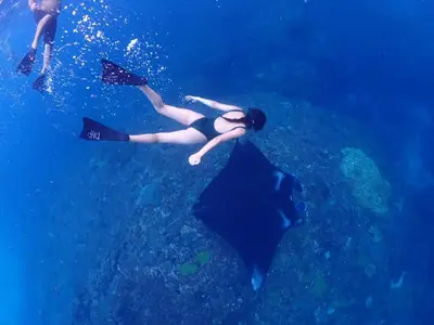 a woman swimming in the ocean next to a stingray at Круиз на Яхте с Бали на Нуса Пенида in Sanur
