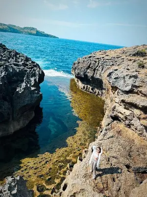 a person standing on a rock near the ocean at Круиз на Яхте с Бали на Нуса Пенида in Sanur
