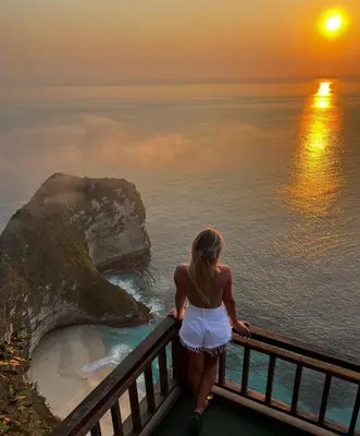 a woman standing on a balcony looking out at the ocean at Круиз на Яхте с Бали на Нуса Пенида in Sanur