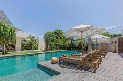 a swimming pool with lounge chairs and an umbrella at Villa Jinjah Soul Luxury 5BR Villa,18m Pool & Garden in Seminyak