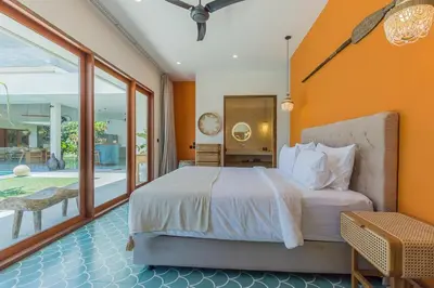a bedroom with a bed with an orange wall at Villa Jinjah Soul Luxury 5BR Villa,18m Pool & Garden in Seminyak