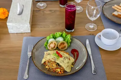 a plate with a burrito and vegetables on a table at Villa Mandari in Seminyak