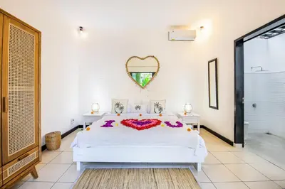 a bedroom with a bed and a heart shaped mirror at Villa Mandari in Seminyak