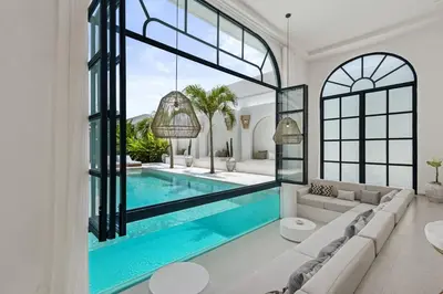 a living room with a swimming pool and a large window at Chic All-White Villa with Pool and Fire Pit in Jimbaran