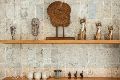 a shelf with several figurines of cats on it at Chic All-White Villa with Pool and Fire Pit in Jimbaran