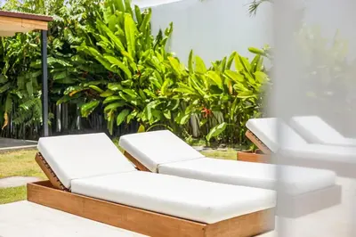 a pair of white chaise lounge chairs on a patio at Chic All-White Villa with Pool and Fire Pit in Jimbaran