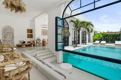 a living room with a swimming pool and a house at Chic All-White Villa with Pool and Fire Pit in Jimbaran