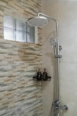 a shower in a bathroom with a stone wall at Villa Alase - Pool, Garden, Peace in Seminyak