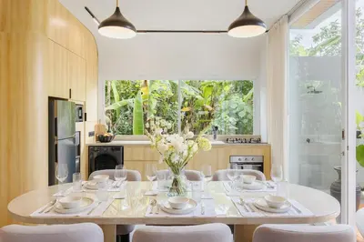 a dining room with a white table and chairs at Aura Umalas - Futuristic 2BR Rooftop Villa with Green Views in Kerobokan