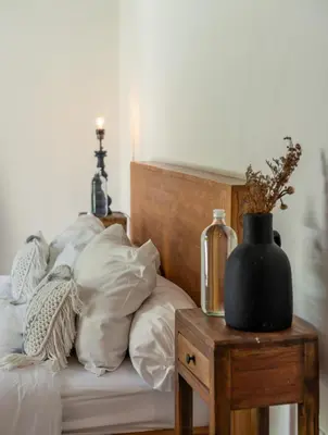 a bed with white pillows and a black vase on a table at 3BR Green Oasis downtown Berawa Canggu in Canggu