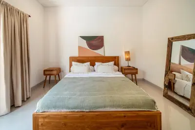 a bedroom with a wooden bed and a mirror at 3BR Green Oasis downtown Berawa Canggu in Canggu