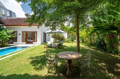 a garden with a table and chairs next to a pool at 3BR Green Oasis downtown Berawa Canggu in Canggu