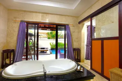 a bath tub in a bathroom with purple curtains at Private Pool Villas Kuta Bali in Badung