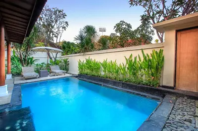 a large blue swimming pool next to a building at Private Pool Villas Kuta Bali in Badung