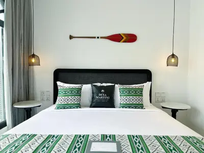 a bedroom with a bed with green and white pillows at Martini Beachside Villa 5 in Canggu