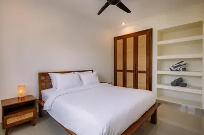 a bedroom with a white bed and a wooden door at Villa Batu Putih 3 Seminyak in Seminyak