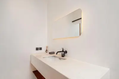 a white bathroom with a sink and a mirror at Casa Nalani in Bali in Kerobokan