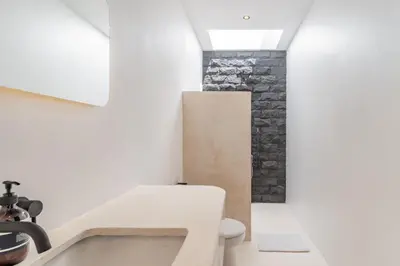 a bathroom with a toilet and a stone wall at Casa Nalani in Bali in Kerobokan