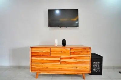 a wooden dresser with a television on a wall at Kamar Kodel2 Apt in Seminyak