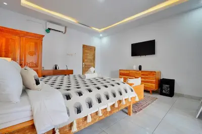 a bedroom with a large bed and a television at Kamar Kodel2 Apt in Seminyak