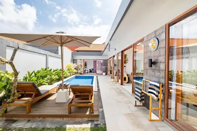 an outdoor deck with chairs and an umbrella next to a swimming pool at Brand new - spacious complex Villas Virland - center Seminyak in Seminyak