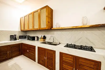 a kitchen with wooden cabinets and a sink at Brand new - spacious complex Villas Virland - center Seminyak in Seminyak