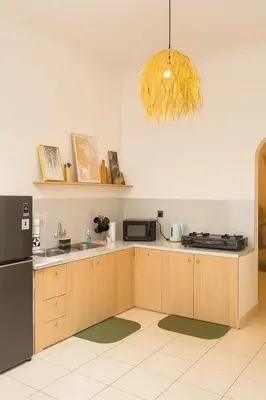 a kitchen with wooden cabinets and a black refrigerator at Villa Cempaka - Pemogan in Denpasar
