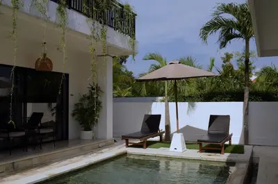 a swimming pool with two chairs and an umbrella at ChinGiack Apartments Canggu Pool and Terrace in Canggu
