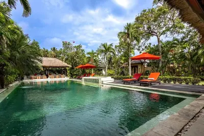 a pool at a resort with chairs and umbrellas at 5 Bedroom Luxury Villa With Huge Garden & Pool 150-Metres To Seminyak Beach in Seminyak