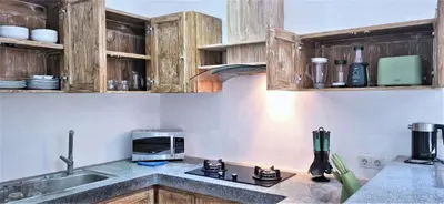 a kitchen with wooden cabinets and a microwave at Tropical 2br private pool Villa in central Seminyak in Seminyak