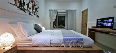 a bedroom with a white bed and a tv at Tropical 2br private pool Villa in central Seminyak in Seminyak