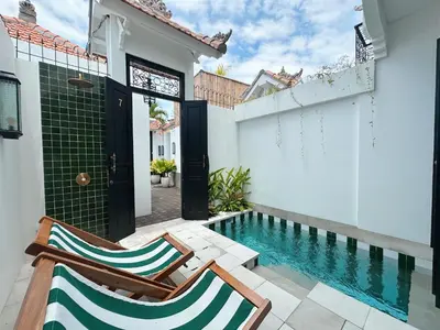 a home with a swimming pool and two chairs next to a house at Martini Beachside Villa 7 in Canggu