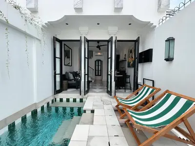 a house with a swimming pool and two chairs at Martini Beachside Villa 7 in Canggu