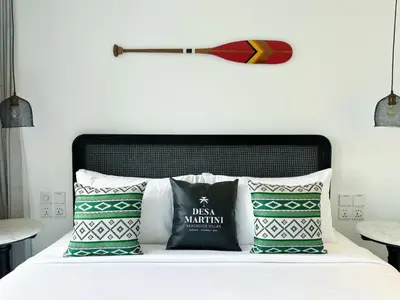 a bed with two pillows and a baseball bat on the wall at Martini Beachside Villa 7 in Canggu