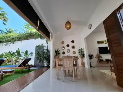 an open living room with a wooden table and chairs at Villa A La Cool Seminyak in Seminyak