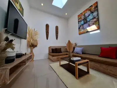 a living room with a couch and a tv at Villa A La Cool Seminyak in Seminyak