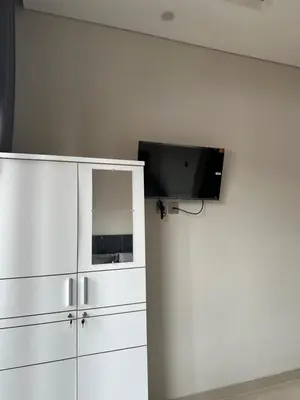a tv on a wall next to a white cabinet at Kubu Gandi Homestay in Denpasar