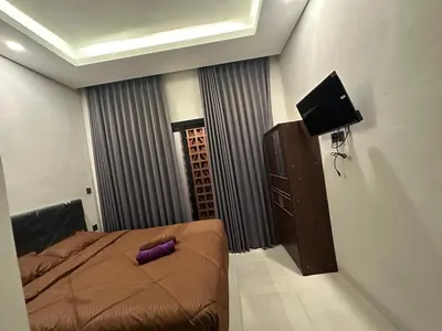 a bedroom with a bed with a purple pillow on it at Kubu Gandi Homestay in Denpasar