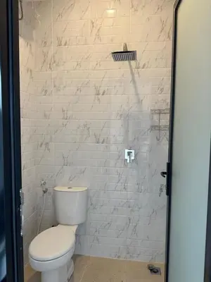 a bathroom with a toilet and a white brick wall at Kubu Gandi Homestay in Denpasar
