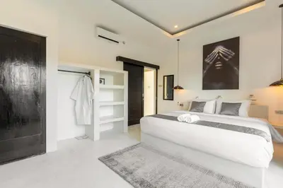 a bedroom with a large white bed and a closet at Aaryan Villa 1 in Seminyak