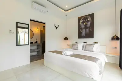 a white bedroom with a large bed in it at Aaryan Villa 1 in Seminyak