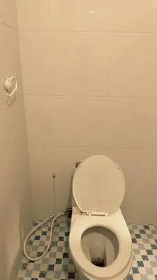 a white toilet in a bathroom with a tile floor at kerobokan cozy house by kenta in Seminyak