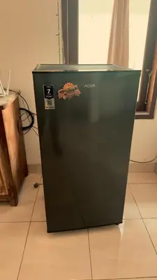 a black refrigerator sitting on a tile floor at kerobokan cozy house by kenta in Seminyak