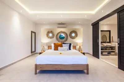 a bedroom with a bed and two mirrors on the wall at Villa Hugo in Canggu