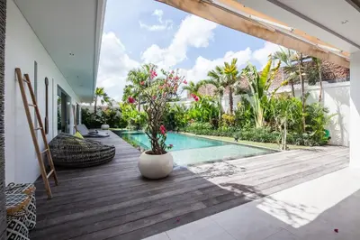 a house with a swimming pool and a wooden deck at Villa Hugo in Canggu